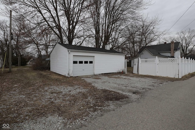 detached garage featuring driveway and fence