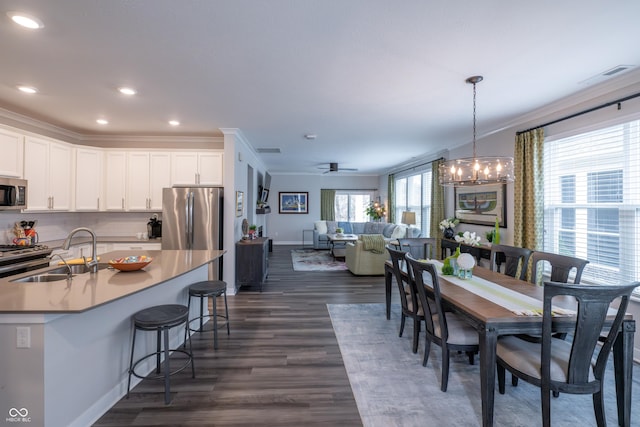 dining area with ceiling fan with notable chandelier, ornamental molding, dark hardwood / wood-style flooring, and sink