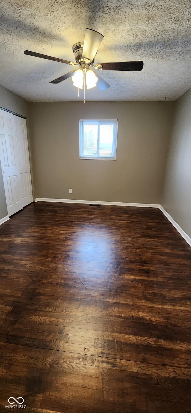 empty room with ceiling fan, a textured ceiling, and dark hardwood / wood-style flooring