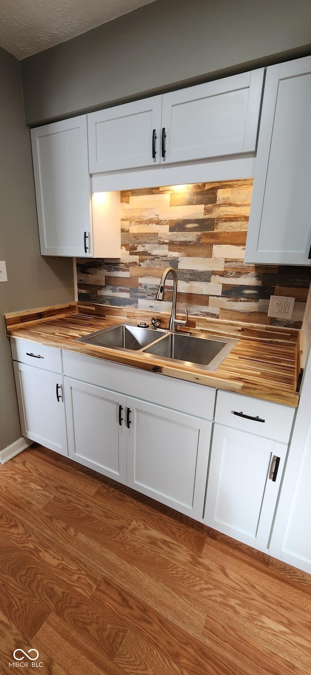 kitchen featuring white cabinetry, sink, backsplash, and light wood-type flooring