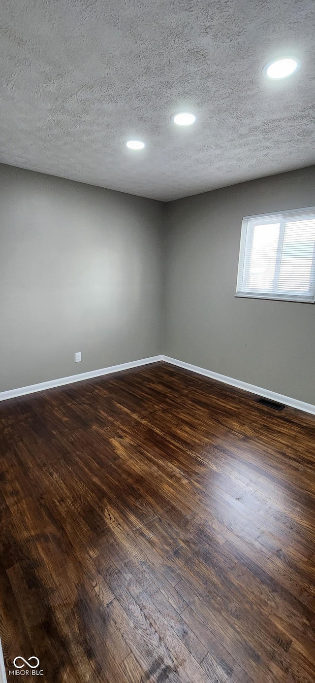 empty room with dark wood-type flooring and a textured ceiling