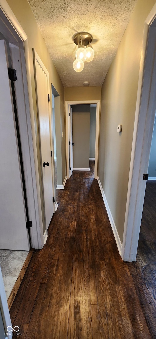 hall with dark hardwood / wood-style flooring and a textured ceiling