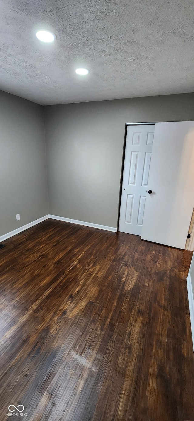 unfurnished room with dark hardwood / wood-style flooring and a textured ceiling