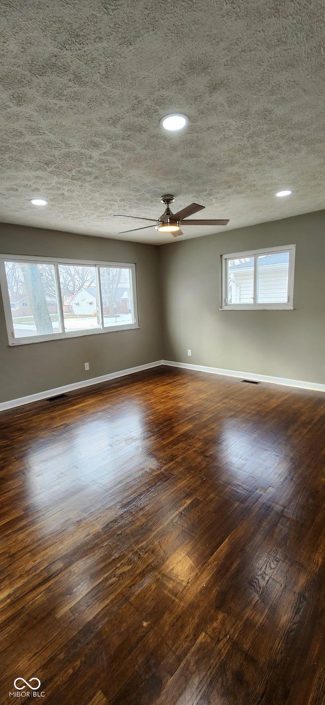 unfurnished room with ceiling fan, dark wood-type flooring, and a textured ceiling