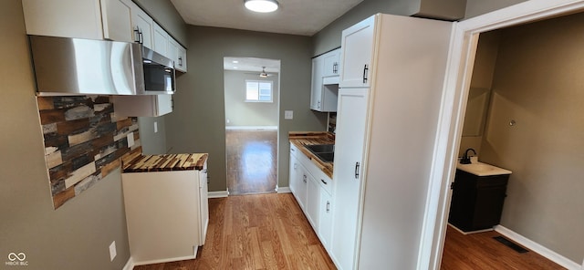 kitchen featuring white cabinetry, wooden counters, black electric stovetop, ceiling fan, and light hardwood / wood-style flooring