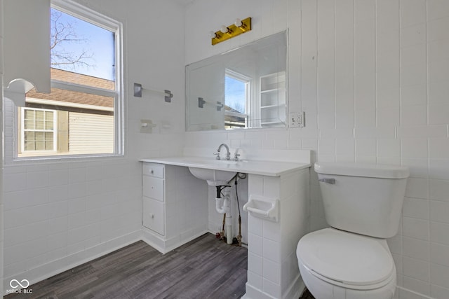 bathroom with wood-type flooring, a healthy amount of sunlight, and tile walls