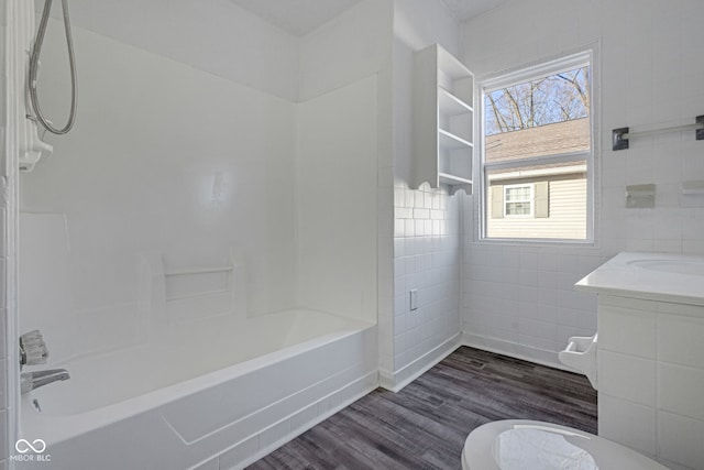 full bathroom with hardwood / wood-style floors, tile walls, shower / bath combination, vanity, and toilet