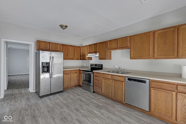 kitchen featuring appliances with stainless steel finishes, sink, and light hardwood / wood-style flooring