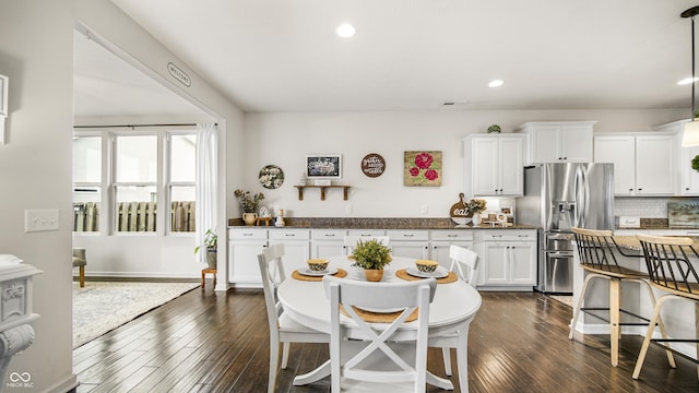 kitchen featuring stainless steel refrigerator with ice dispenser, dark hardwood / wood-style floors, hanging light fixtures, and white cabinets