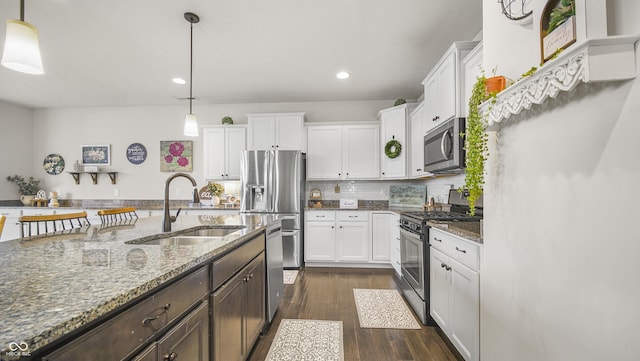 kitchen featuring stainless steel appliances, hanging light fixtures, sink, and white cabinets