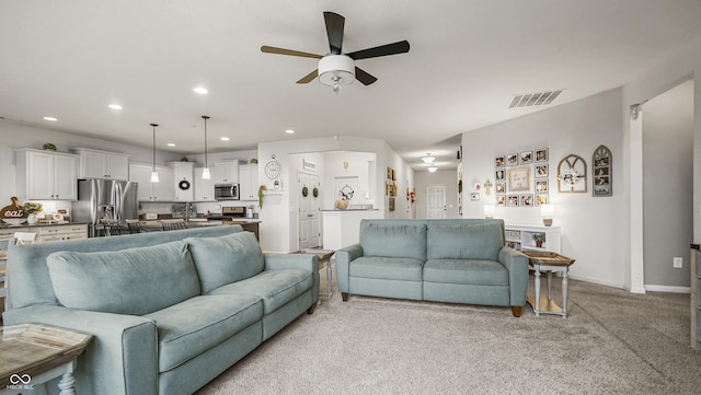 living room featuring ceiling fan, light colored carpet, and sink