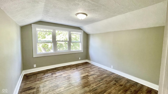 additional living space with dark hardwood / wood-style flooring, vaulted ceiling, and a textured ceiling