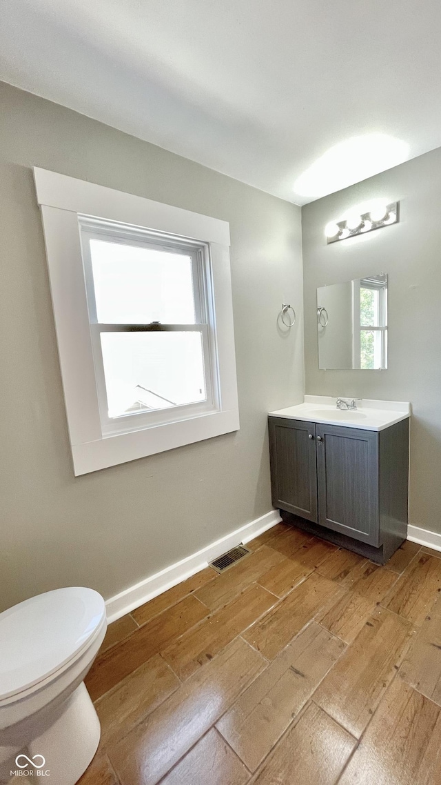 bathroom featuring wood-type flooring, vanity, and toilet