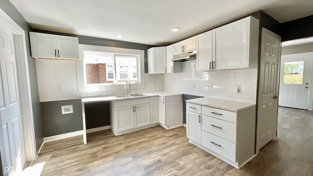 kitchen with white cabinetry, sink, tasteful backsplash, and light hardwood / wood-style floors