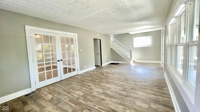 unfurnished room featuring wood-type flooring, french doors, and a textured ceiling