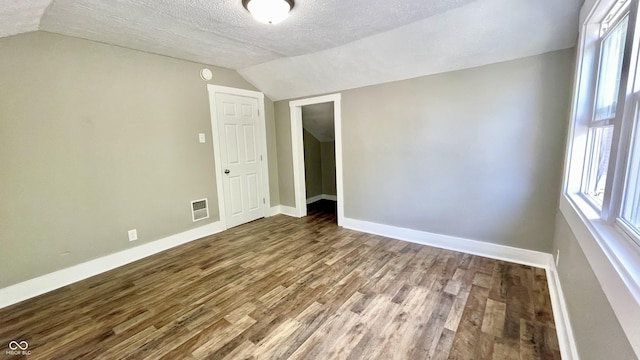 empty room with a healthy amount of sunlight, wood-type flooring, and a textured ceiling