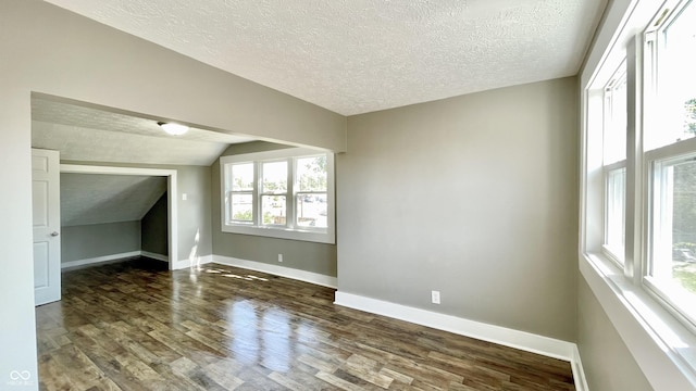 bonus room featuring dark wood-type flooring, lofted ceiling, and a textured ceiling