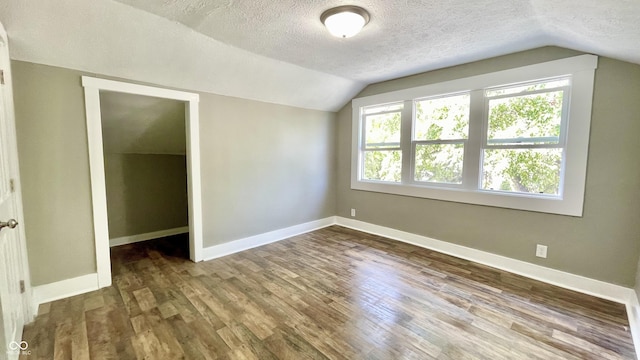 bonus room with lofted ceiling, hardwood / wood-style floors, and a textured ceiling