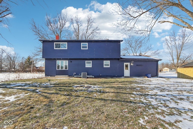 snow covered rear of property featuring central AC and a lawn