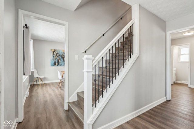 stairs with wood-type flooring and a textured ceiling