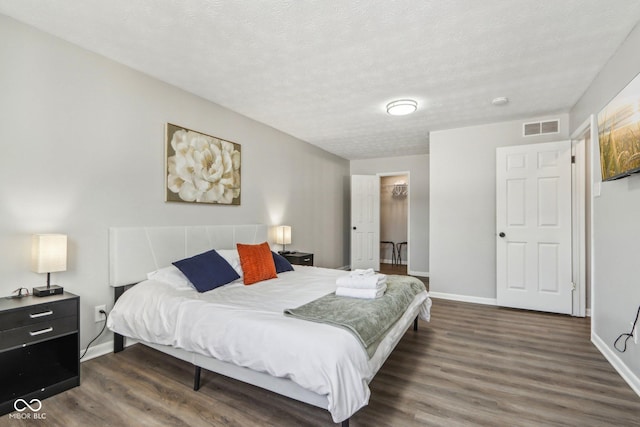 bedroom featuring a spacious closet, a textured ceiling, and dark hardwood / wood-style flooring