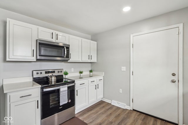 kitchen with stainless steel appliances, dark hardwood / wood-style floors, and white cabinets