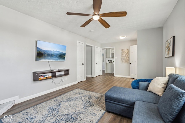 living room with ceiling fan, a textured ceiling, and dark hardwood / wood-style flooring