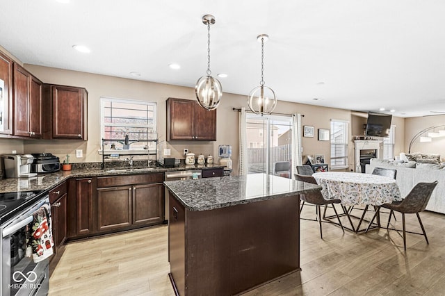 kitchen with pendant lighting, dark stone counters, stainless steel electric stove, and a center island