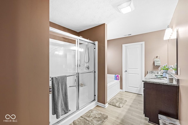 bathroom featuring vanity, hardwood / wood-style floors, independent shower and bath, and a textured ceiling