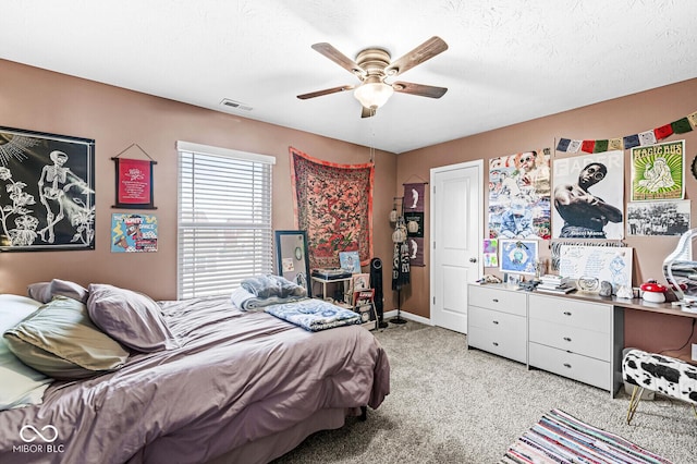 carpeted bedroom featuring ceiling fan and a textured ceiling