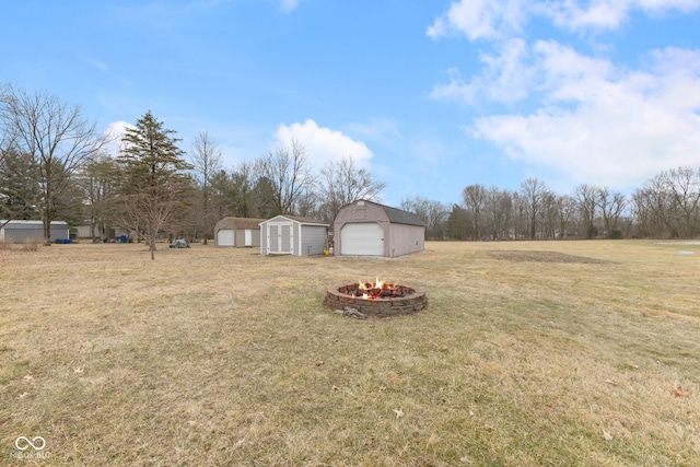 view of yard featuring an outdoor fire pit, a shed, and a garage