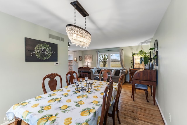 dining space featuring hardwood / wood-style floors and a notable chandelier