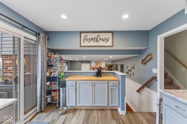 kitchen featuring white cabinetry, light hardwood / wood-style floors, a textured ceiling, and butcher block countertops