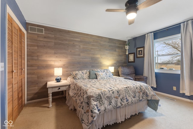 carpeted bedroom with ceiling fan and wood walls