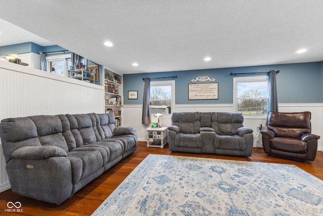 living room with built in features, dark hardwood / wood-style flooring, a textured ceiling, and a wealth of natural light