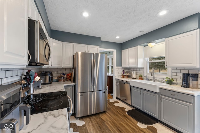 kitchen featuring white cabinetry, appliances with stainless steel finishes, sink, and light stone counters