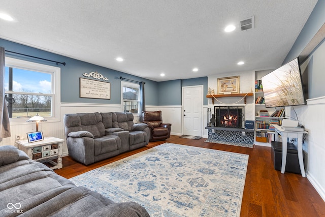 living room featuring a large fireplace, a wealth of natural light, a textured ceiling, and dark hardwood / wood-style flooring