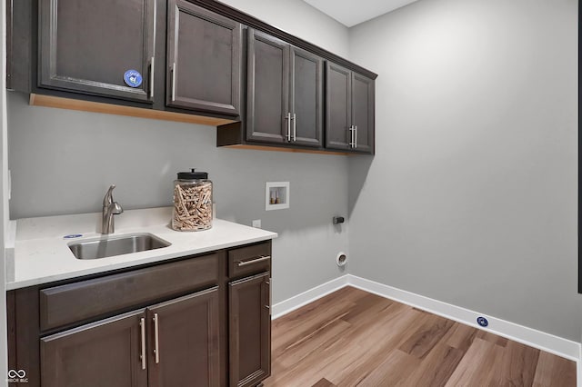 laundry area featuring hookup for a washing machine, sink, cabinets, and light hardwood / wood-style floors