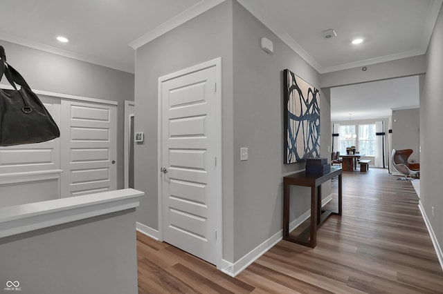 hallway with hardwood / wood-style flooring, crown molding, and a notable chandelier