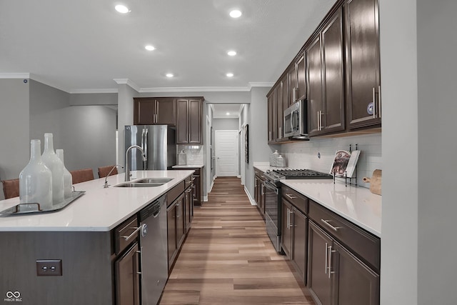 kitchen featuring tasteful backsplash, stainless steel appliances, sink, and an island with sink