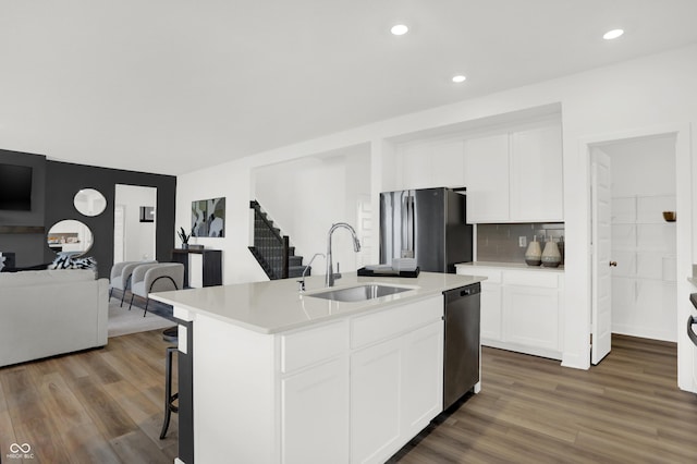 kitchen featuring black refrigerator, sink, an island with sink, and white cabinets