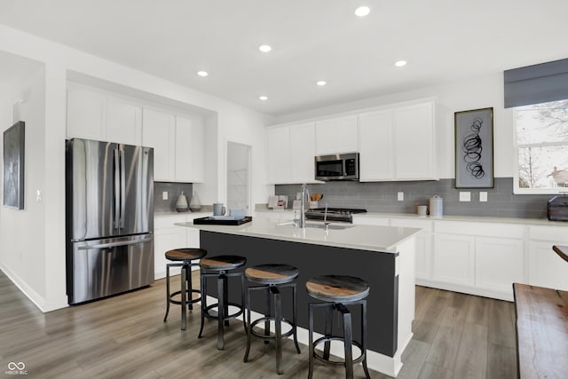 kitchen featuring stainless steel appliances, sink, an island with sink, and white cabinets