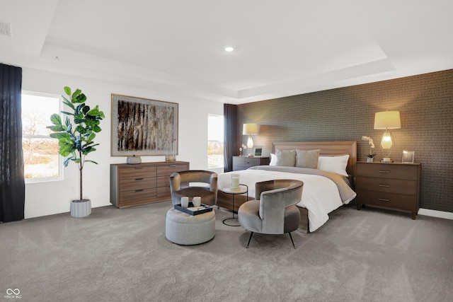 bedroom featuring multiple windows, a tray ceiling, and light carpet