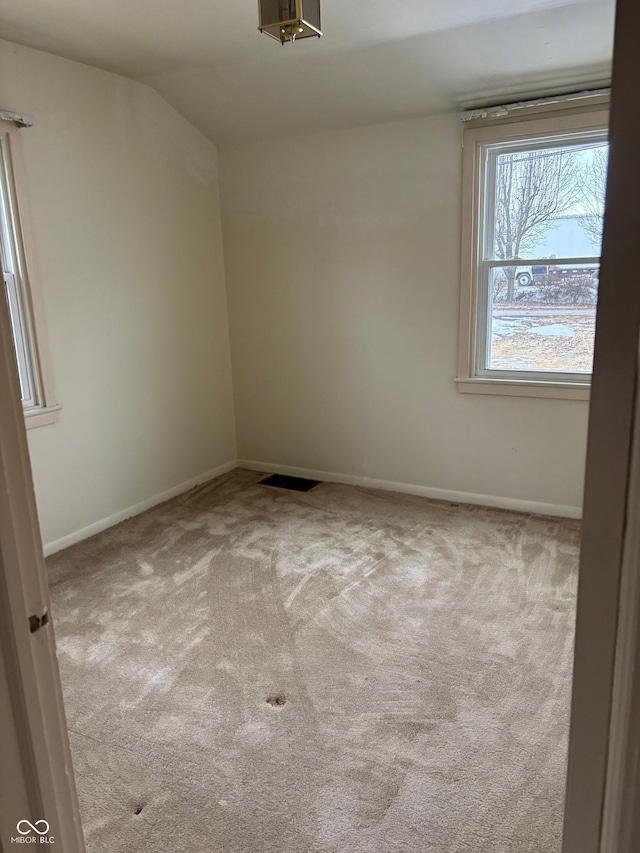 carpeted empty room with vaulted ceiling