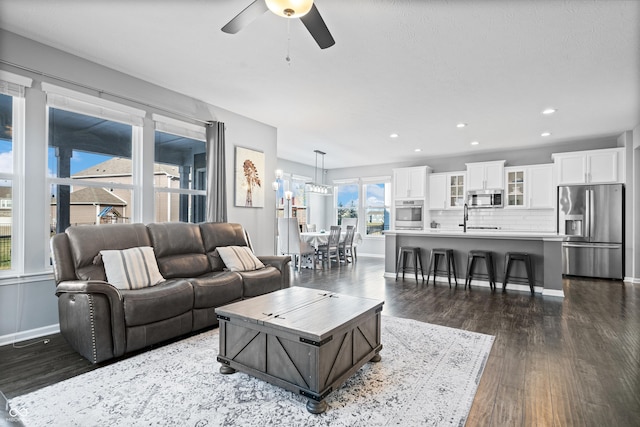 living room featuring dark wood-type flooring and ceiling fan