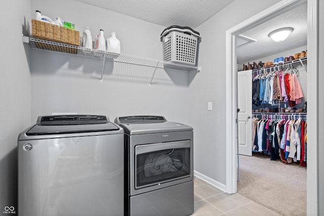 laundry area featuring light colored carpet, washing machine and clothes dryer, and a textured ceiling