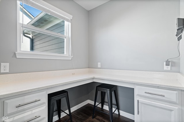 home office with dark hardwood / wood-style floors and built in desk