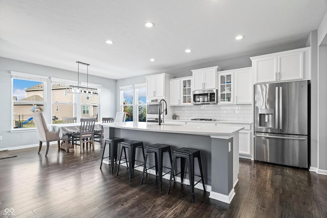 kitchen with sink, white cabinetry, pendant lighting, stainless steel appliances, and a kitchen island with sink