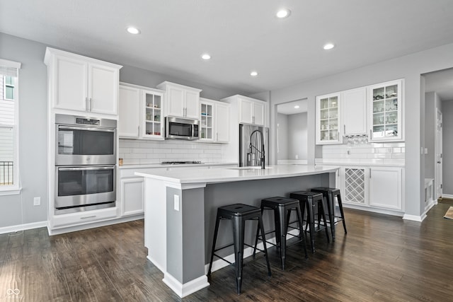 kitchen featuring sink, a breakfast bar, stainless steel appliances, white cabinets, and a center island with sink