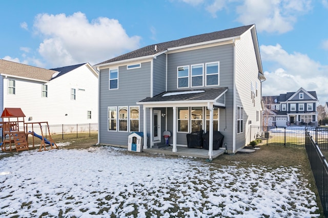 snow covered house with a patio and a playground